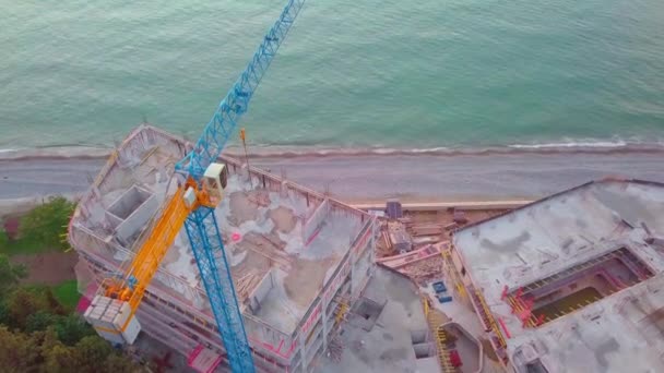 Gru sta lavorando sulla vista del cantiere da un drone sullo sfondo del mare. — Video Stock