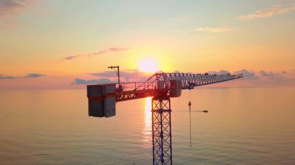 Grúa al atardecer desde una vista de pájaro, los rayos del sol pasan a través de la estructura de la grúa. — Vídeo de stock