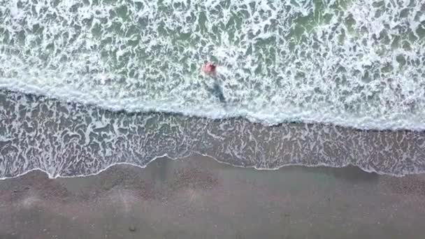 Strzelając z drona, kobieta wchodzi do morza i raduje się. szczęście. — Wideo stockowe