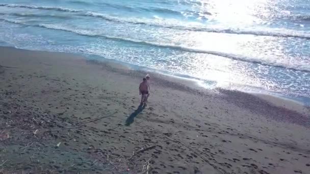 Een man en een vrouw lopen over een verlaten strand, in de branding.. — Stockvideo