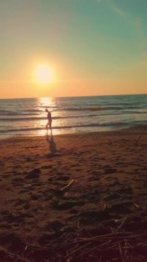 İnsansız hava aracı, deniz kıyısında küloduyla dolaşan bir adamın fotoğrafını çeker.,