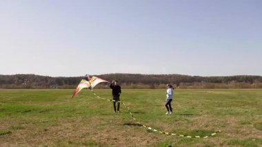 Mutlu genç çift, güneşli bir günde, güzel mavi gökyüzüne karşı birlikte uçurtma uçurarak, açık hava yaşam tarzının ve eğlence aktivitelerinin tadını çıkarıyorlar.