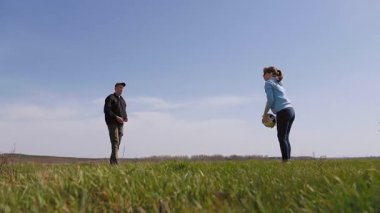 Neşeli genç adam ve kadın güneşli bir günün tadını çıkarıyorlar, güzel yeşil bir çayırda voleybol topu atıp yakalıyorlar. İlkbaharda doğada aktif yaşam tarzı ve boş zaman aktiviteleri