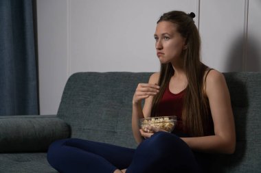 Genç bir kadın rahat bir kanepede dinleniyor. Bir kase patlamış mısırla film gecesinin tadını çıkarıyor. Huzurlu bir akşam boyunca ev sineması eğlencesinin heyecanına dalmış.