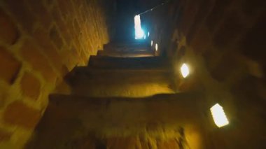 Birinci şahıs bakış açısıyla karanlık, dolambaçlı bir merdivenden aşağı eski bir kule ya da kale içinde, duvarların ışıklarıyla aydınlatılmış taş basamaklar ve aşağıdaki açıklıktan gelen parlak bir ışık.