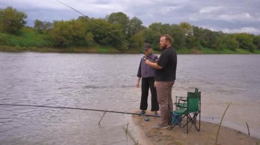 Genç adam bir kadına nehir kıyısında nasıl balık tutulacağını öğretiyor. Bulutlu bir sonbahar gününde, sakin açık havada balık tutmayı ve makarayı nasıl monte edeceğini gösteriyor.