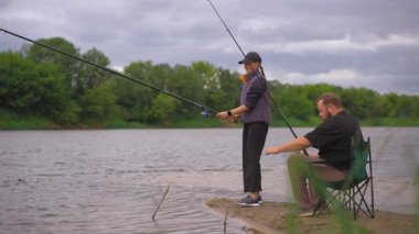 Romantik bir çift nehir kıyısında duruyor ve bulutlu bir günde dönen çubuklarla balık tutuyor, boş zamanlarının keyfini çıkarıyor ve doğada birlikte kaliteli zaman geçiriyorlar.