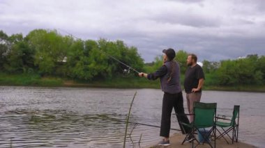Genç bir kadın nehir kıyısından olta atarken sakallı bir adam tekniğini izliyor. Birlikte sakin bir günün tadını çıkarıyor ve bulutlu bir günde yakalamayı bekliyor.