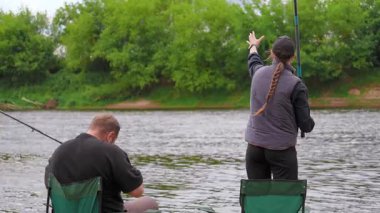Romantik bir çift nehir kıyısında duruyor ve bulutlu bir günde dönen çubuklarla balık tutuyor, boş zamanlarının keyfini çıkarıyor ve doğada birlikte kaliteli zaman geçiriyorlar.
