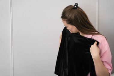 Beyaz kadın elinde siyah kadife giysiler tutuyor, ne giyeceğine karar veriyor, hazırlanıyor, önemli bir etkinliğe hazırlanıyor, moda, elbise, tarz.