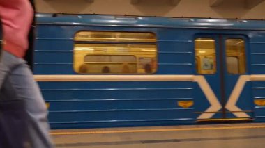 Minsk, Belarus - 13 Temmuz 2024: Mavi metro treni istasyona varan yolcularla birlikte kısa bir süre için durdu, kapılar açılıp kapanıyor ve kalkıyor, metro istasyonunda boş bir platform bırakıyor.