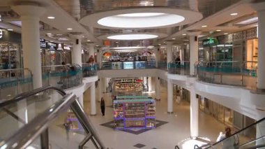 Minsk, Belarus - 13 Temmuz 2024: Geniş görüşlü modern alışveriş merkezi, yürüyen merdivenler, çeşitli dükkanlar ve müşteriler tarafından birbirine bağlanmış durumda.