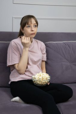 Sıkıcı genç bir kadın evinde rahat bir kanepede oturmuş, sıkıcı bir film izlerken cam kaseden patlamış mısır yiyordu, akşam eğlencesi seçiminden memnun değildi.