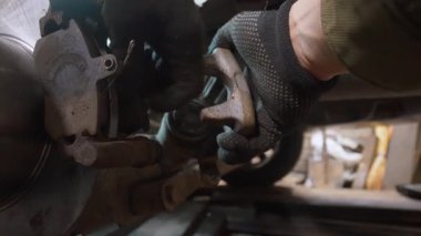 Profesyonel tamirci eldiven takıyor. Bir otomotiv tamir atölyesinde fren pedlerini değiştirdikten sonra fren ayarını merkezin üzerine dikkatlice yerleştiriyor.