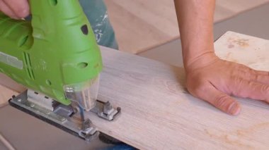Elektrikli yapboz kullanarak işçilerin ellerinin yakın plan çekimleri bir parça kaplama döşeme, hassas marangozluk gösterimi ve yeni döşeme montajı için onarım