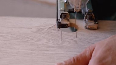 Tahta kaplama levhaya delik açmak için yapboz kullanan deneyimli işçilerin elleri yakın plan, bıçak hareket ederken uçan talaş, ayrıntılı marangozluk işlemini gösteren