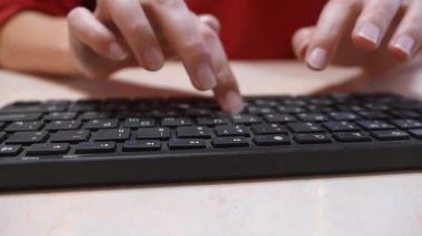 Bir kadının elinin siyah bir klavyeye yazı yazarken, ofis işini, iletişimi, programlamayı ya da çalışmasını temsil ederken, masadaki tuşlara basan parmaklarının hareketine odaklanırken yakın plan görüntüsü