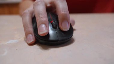 Bir kadının elinin yakın plan görüntüsü, masadaki siyah kablosuz bilgisayar faresini kullanarak, çalışırken, çalışırken, çalışırken veya internette gezinirken, düğmelere basarak ve tekerleği kaydırarak