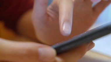 Yakın plan: modern akıllı telefonda mesaj yazıp, kaydıran, internette gezinen evde internet iletişimi ya da eğlence arayan, bakımlı genç bir kadının elleri.