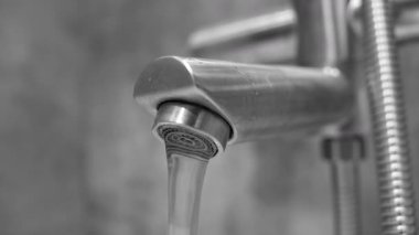 Banyodaki modern paslanmaz çelik musluktan akan temiz musluk tüketim, elektrik giderleri, tesisat, hijyen ve çevre koruma gibi kavramları temsil ediyor.