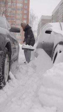Araçlar, yoğun sürüş ve kar arasında araba kazan kadın, kürek ve kazıyıcı ile acele hareket, kapalı garaj yolu ve kaldırılmış kaput, soğuk gri gökyüzü ve şehir apartman seti, kararlı
