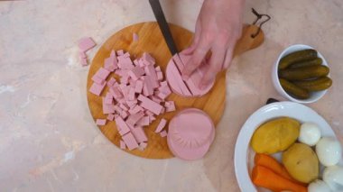 Dilimlerle yemek pişirmek. Dilimlenmiş sosis ve sebzeli mutfak sahnesi. Elleri yemek pişiren, sosis doğrayan ve sebze doğrayan rahat bir mutfak ortamı.