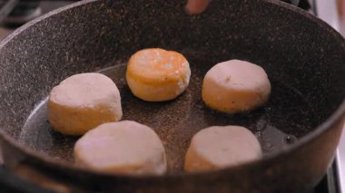 Altın yuvarlak kahverengi tavalı, kahvaltı şefi fırında çatalsız tavada küçük krep disklerini çeviriyor, yakın çekimde köşeleri çevirip kahverengi, cızırtılı aromayı bile başarıyor.