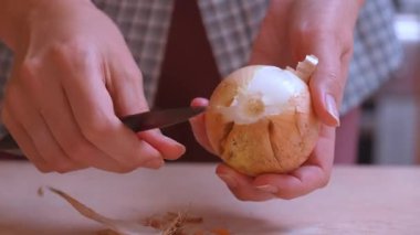 Eller soğan soyuyor. Kahverengi soğanın dış katmanlarını yemek hazırlamak için çıkarıyorlar. Eller dikkatlice yaklaşsın. Kahverengi soğanın dış katmanlarını küçük bir bıçakla soyun.