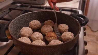 Kıtır kıtır köfte ve köfte pişir. Yemek pişirme sürecine yakın çekim. Eller sıcak tavadaki köfteleri kıtır kıtır olana kadar döndürdü.