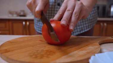 Şef olgun domatesi kesim tahtasında hazırlıyor. Elleri bıçakla sulu olgun domates doğrayan ev mutfağı. Tahtada taze olgun domates, sabit eller ve şef bıçağıyla hazırlanıyor.