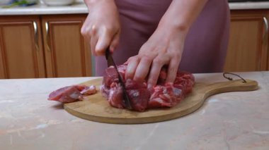 Beyaz kadın çiğ et veya domuz eti dilimliyor, kendine güvenen eller güveç için parça kesiyor, bıçak ve mermer kaplama, sıcak ev yemeği, düzenli ev hazırlığı.