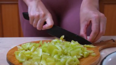 Biber kesen kadınla Parlak Mutfak. Salata için yeşil biber doğrayan bir kadının canlı sahnesi. Kadın Canlı Mutfak Ayarlarında Taze Yeşil Biberleri Uzman Dilimliyor