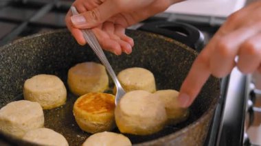 Tavada kızartılmış altın bisküviler, çatal kullanarak ev yemeği küçük yuvarlak peynirli kekler ya da krepler gaz sobasında sıcak tereyağlı kabuk, yumuşak cızırtı, sabah mutfağı, dokunulabilir eller.