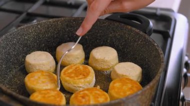 Tavada kızartılmış altın bisküviler, çatal kullanarak ev yemeği küçük yuvarlak peynirli kekler ya da krepler gaz sobasında sıcak tereyağlı kabuk, yumuşak cızırtı, sabah mutfağı, dokunulabilir eller.