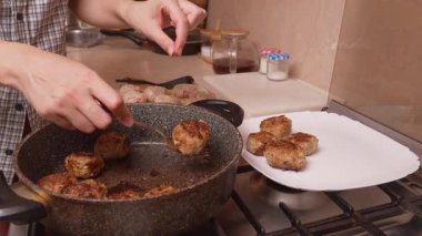 Kapalı Çekim Eller Kahverengi Köfteleri Pan 'dan Tabak' a aktarıyor, Ev Aşçısı çatal ve Spatula ile porsiyonları, Sıcak Mutfak Sahnesi Vurgulama Hizmeti ve Aile Yemeği Hazırlama