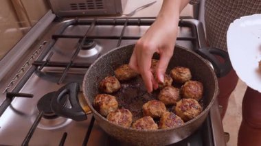 Eller dikkatlice köfteleri tavaya yerleştirir, aşçı sıraları dizer ve servis etmeden önce son seviyeyi ekler, soba ve tabak yan tarafta pratik bir atmosfer yaratır.