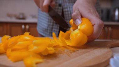 Tahta yüzeyde Sarı Biber Doğrama. Elleri Dilimleyen Sarı Biber 'in Yakın Çekimi. Pişirme ve Salata Hazırlama İçin Sarı Çan Biberi Ayrıntılı Görünümü