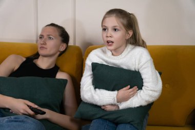 Evde sarı bir kanepede oturan iki kız kardeş korku ve şaşkınlıkla karışık bir film izleyip rahat bir akşam aile bağı ve rahatlamış eğlence ortamının tadını çıkarıyorlar.