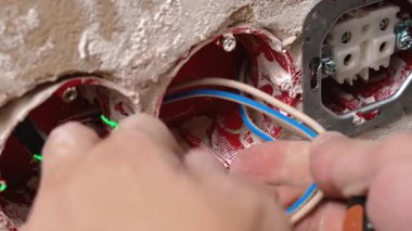 Koltuğun yalıtım malzemelerini ve kondüktörlerini dikkatlice kaldırın. Elektrik teknisyeni mavi ve kahverengi kabloları güvenli bir şekilde terminale bağlarken aynı zamanda yalıtımı kaldırıyor ve kutunun içindeki soketi yönlendiriyor.