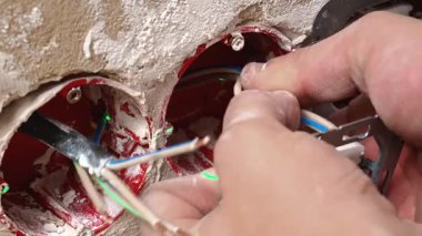 Beyaz teknisyen, duvarda tornavidalı soket mekanizması, vidaları sıkılaştıran ve terminalleri hizalayan yakın çekimli eller, içerideki elektrik tesisatı, temizliği gösteren