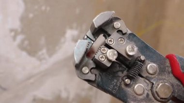 Yakın çekim elektrikçisi mavi kabloyu bir striptizci, açık soketler ve tozlu alçı ile soyar, kabloyu konektör kurulumu için dikkatlice hazırlar ve güvenliği kontrol eder