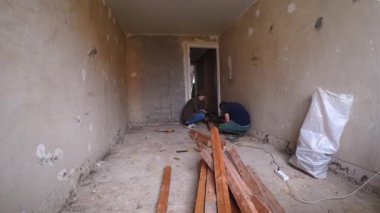 Personel Moloz 'u kaldırın ve boş alandaki yenilenmiş zemini düzenleyin. Esnaflar Yüzeyi Yeniden Yapılandırma Çabalarına Hazırlarken Döşeme Tahtalarını Sırala ve Yığınla