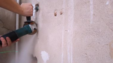 Elektrik işçisi oymacılığı. Elektrikçi El Sanatları Dikey Duvar Çukuru. Yetenekli elektrikçi elektrik tesisatı için duvarı kesiyor. Elektrikçi Elektrik Kanalı İçin Duvarda Siper Oluşturmak İçin Öğütücü Kullanıyor