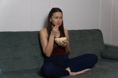 Genç bir kadın rahat bir koltukta oturur, bir filme dalmışken cam kaseden patlamış mısırın tadını çıkarır, evinde rahat ve rahatlatıcı bir akşam geçirir.