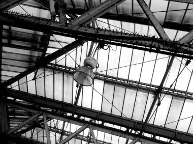 Camdan çatının altındaki kirişten asılı lamba siyah beyaz