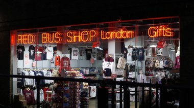 Londra, Birleşik Krallık - 4 Ekim 2019: Londra Kırmızı Otobüs Dükkanı 'nın dışında Londra Hediyelik Eşyalar mağazası gece saatlerinde dükkan ışıklarıyla aydınlatılmış hediyeler ve parmaklıkların arkasından görülen camlarda çoklu yansımalar