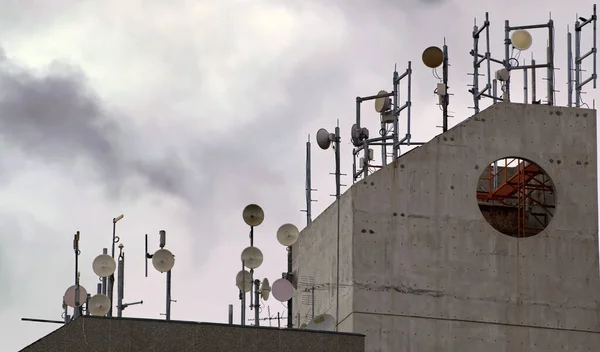 Numerous communication dishes and antennae on concrete roof