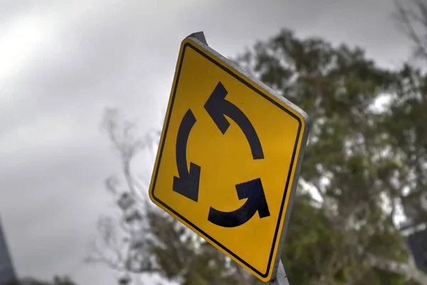 stock image Yellow diamond shaped traffic sign with three black curved arrows indicating roundabout as seen in Mexico