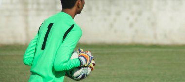 Genç kaleci topu elinde tutuyor.