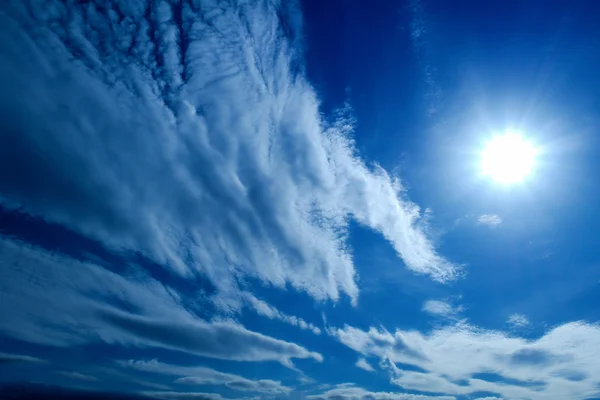 O sol e as nuvens fofas brancas em um céu azul — Fotografia de Stock